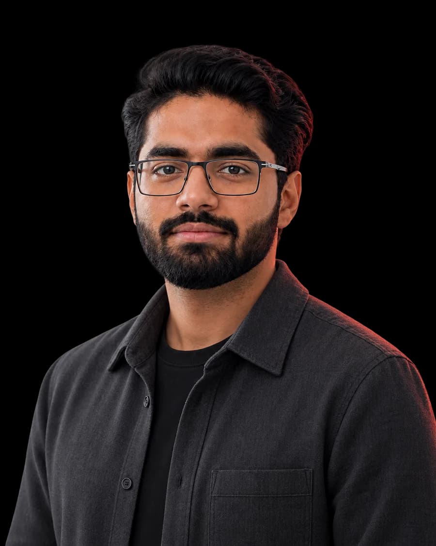 Portrait of Zain Razzaq, wearing glasses and a charcoal overshirt